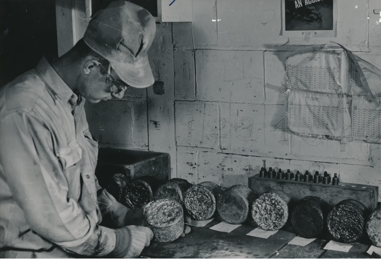 Historic photo of a man working on uranium billets.